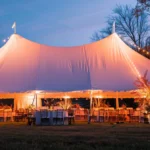 a beautifully arranged tented event adorned with vibrant seasonal decorations, showcasing elegant seating and ambient lighting that conveys a sense of warmth and comfort for guests amidst a picturesque outdoor setting.